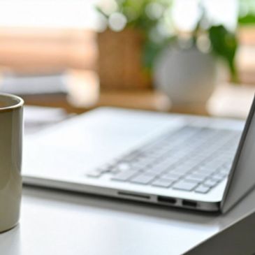 Close-up of a laptop and coffee cup on a desk.