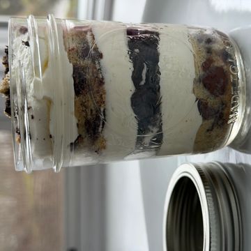 Layered dessert in a mason jar with cream and cookie pieces.