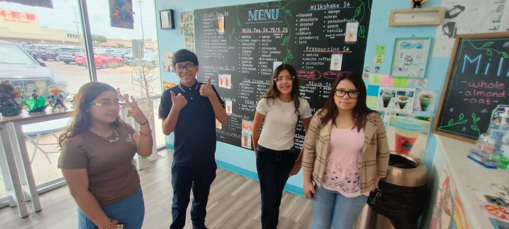 Four young people inside a colorful bubble tea shop posing for a photo.