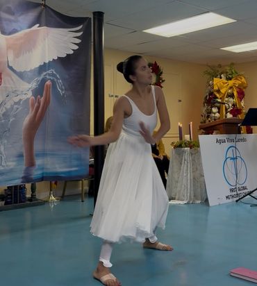 A woman in white performs a spiritual dance indoors.