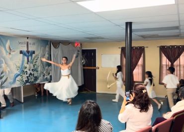 A dancer in a white dress leaps gracefully during a performance indoors.