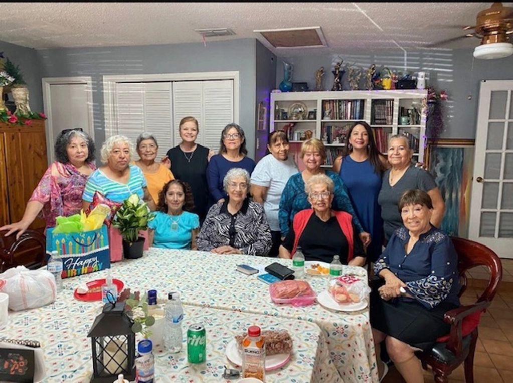 Group of women gathered around a table for a celebration in a cozy room.