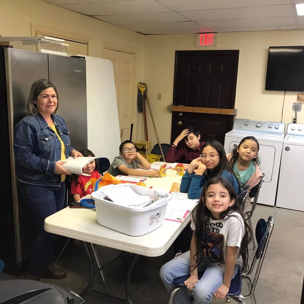 A woman and six children gathered around a table in a laundry room.
