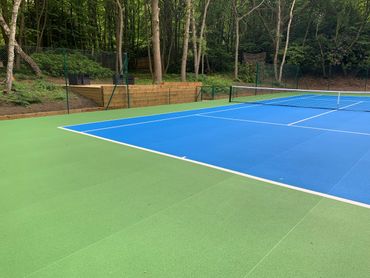 tennis court with green and blue field 