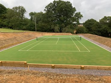 A green tennis court near trees