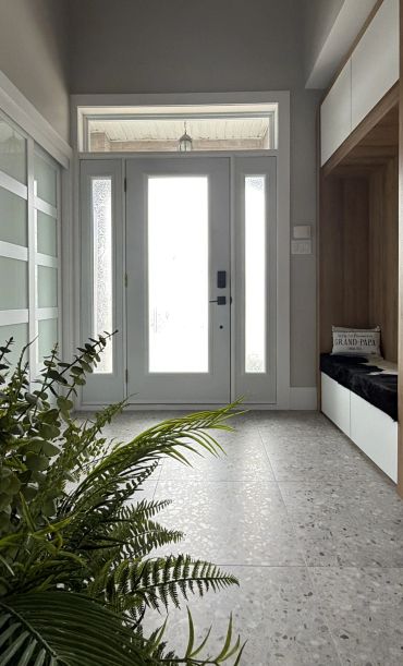 Entrée moderne avec porte blanche et plantes vertes.
