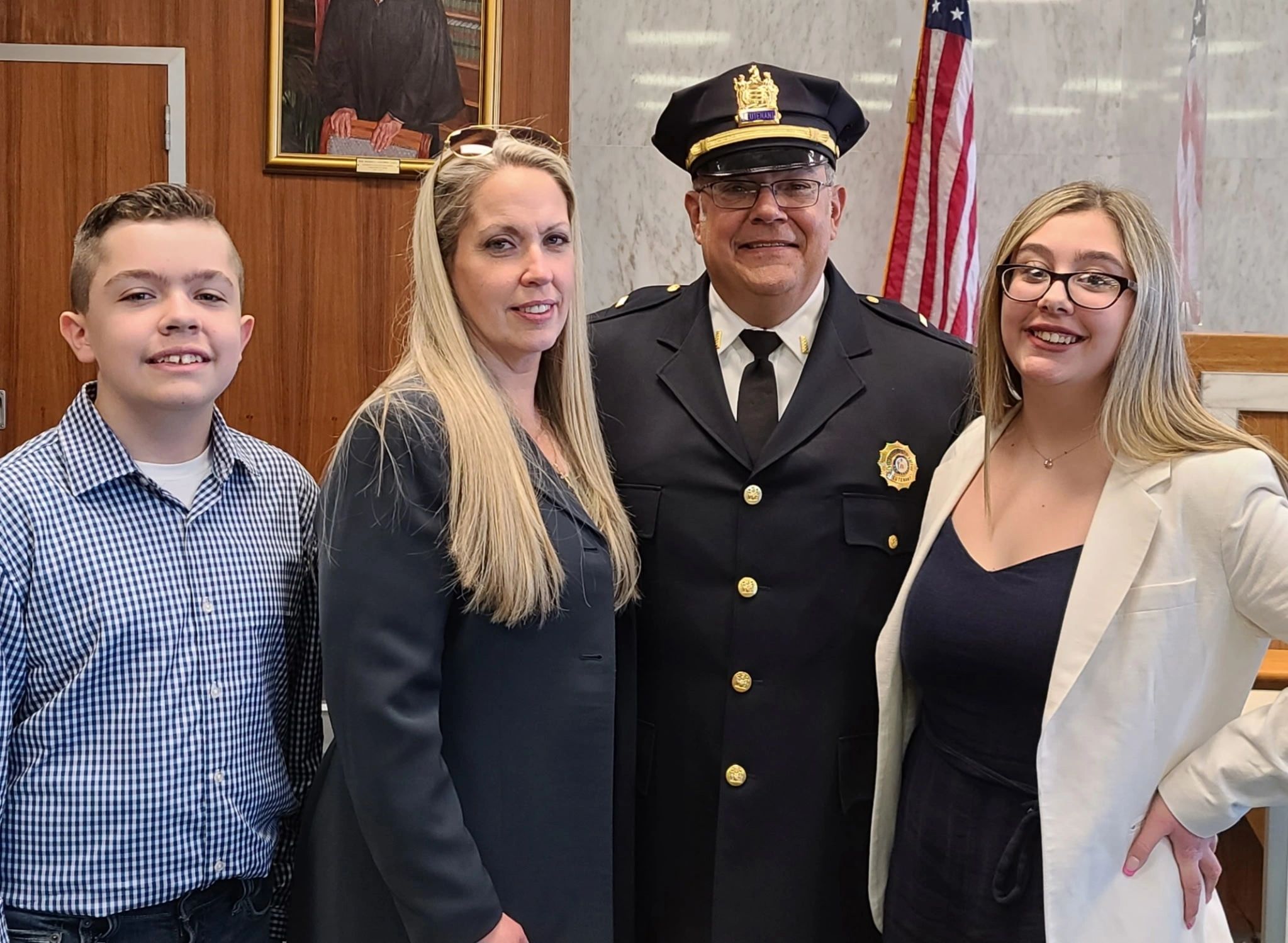 A family posing with a police lieutenant in a formal setting.