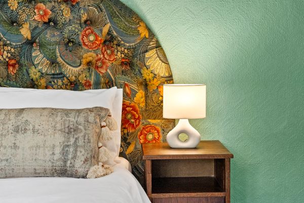 Floral headboard with bedside lamp and table.