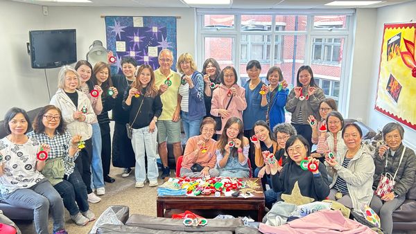 Group of people showing handmade Christmas ornaments indoors.