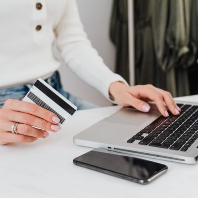 Person holding a credit card and using a laptop for online shopping.