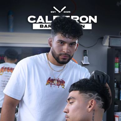 Barber styling a client's haircut with intricate shaved designs on the side.