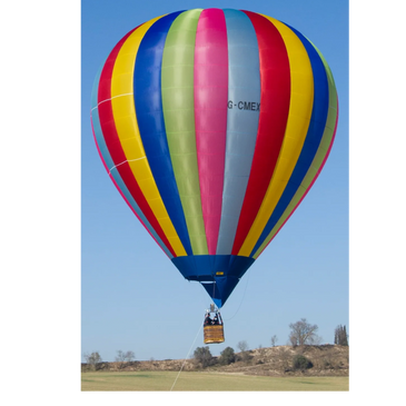 Colorful hot air balloon ascending over a field on a clear day.