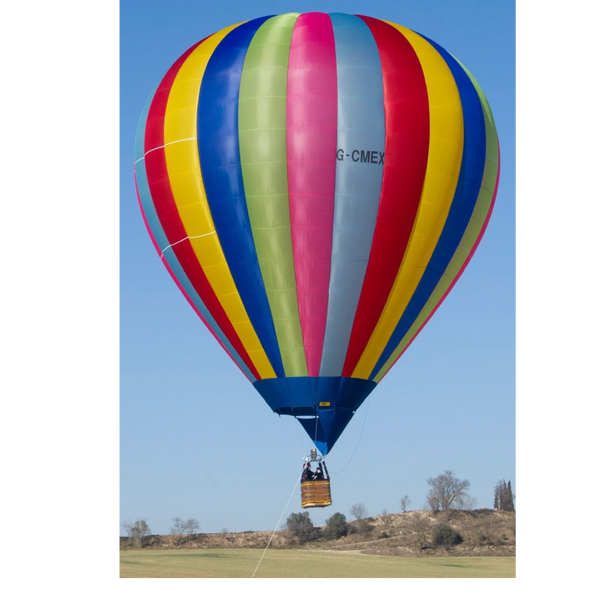Colorful hot air balloon ascending over a field on a clear day.