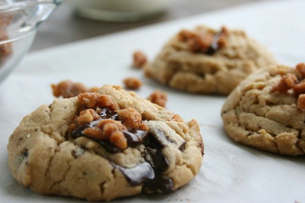 Close-up of chocolate chip cookies with nuts on parchment paper.