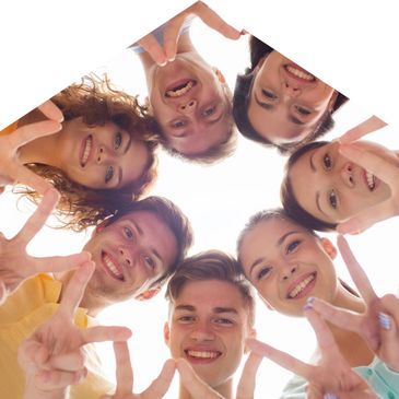 Group of happy young people forming a circle and smiling at the camera.