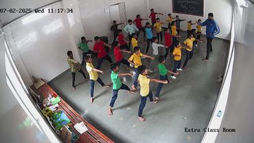 Children practicing martial arts under instructor's guidance in a classroom.
