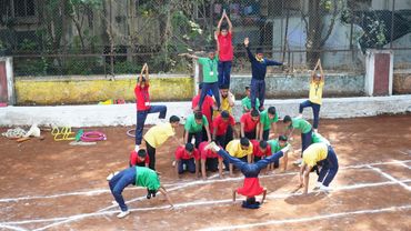 Children performing a coordinated gymnastic pyramid outdoors.