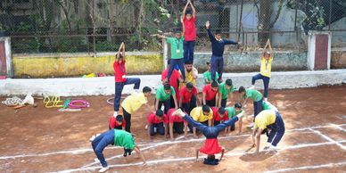 Children performing a coordinated gymnastic pyramid outdoors.