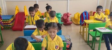 👉 Kindergarten students of St. Francis Academy Shivajinagar, Pune in yellow uniforms drawing and coloring in classroom activities.