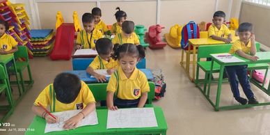 Young children in yellow uniforms drawing and coloring in a classroom.