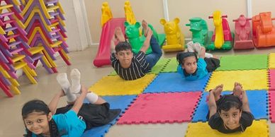 Children doing yoga poses on colorful mats in a playroom.