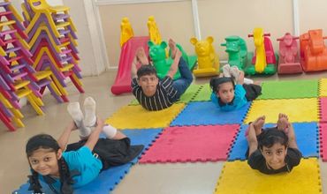 Children doing yoga poses on colorful mats in a playroom.