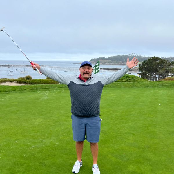 Man celebrating on a golf course with arms raised.