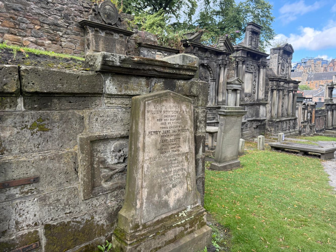 Historic stone graves in Greyfriars Kirkyard with Edinburgh in backdrop.
