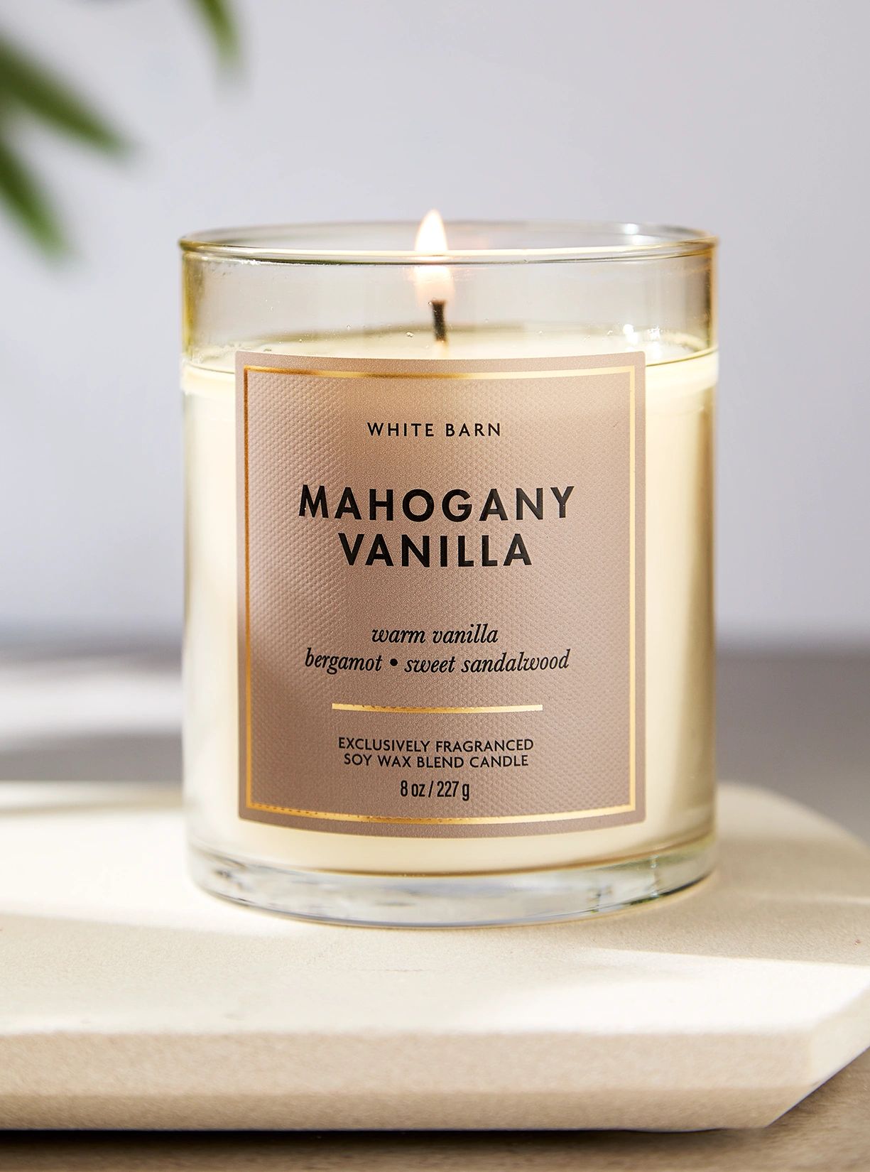 Lit Mahogany Vanilla scented candle in a glass jar.