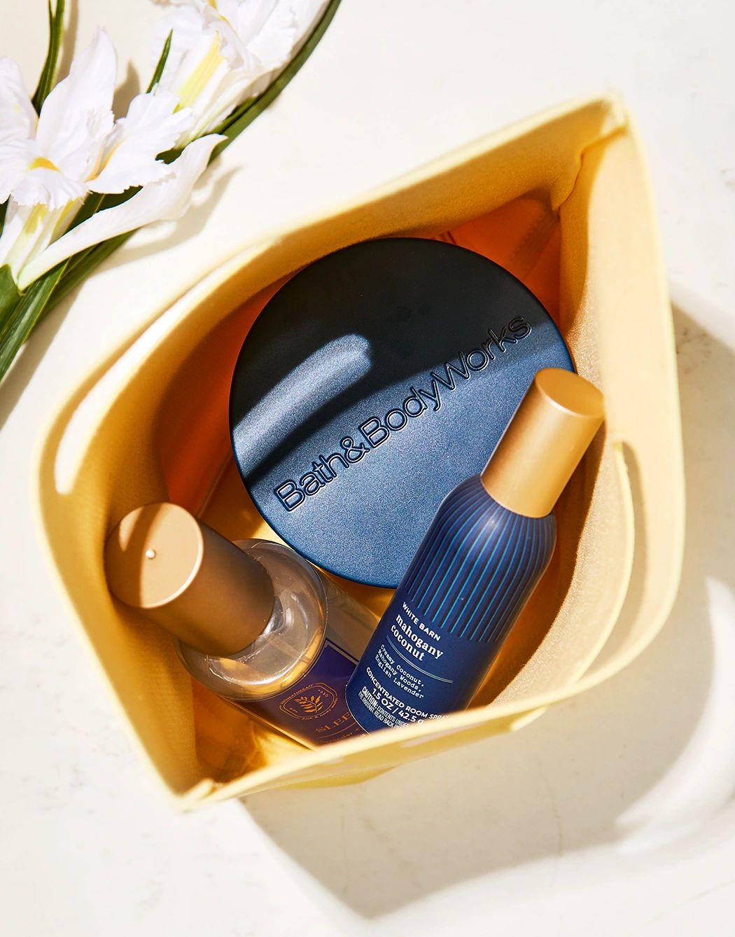 Bath &amp; Body Works products inside a yellow bag with white flowers nearby.
