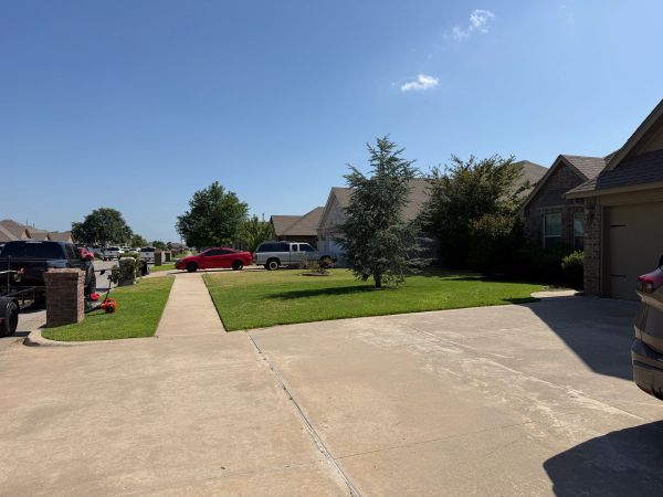Residential neighborhood with parking and green lawns.