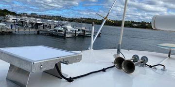 View from a boat overlooking a marina with docked boats under a partly cloudy sky.