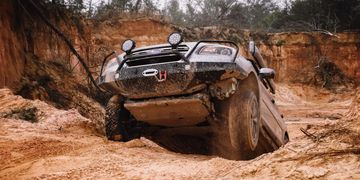 Off-road Subaru tackling rough muddy terrain.