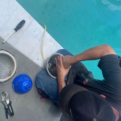 OC’s Pools owner Omar servicing a pool light with the housing open and tools nearby.