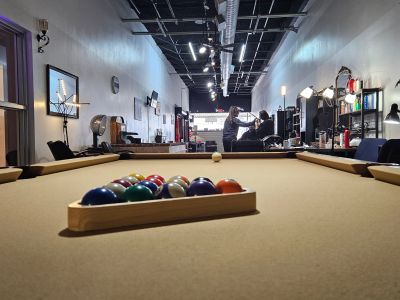 A beige pool table with racked balls in a well-lit recreational room.