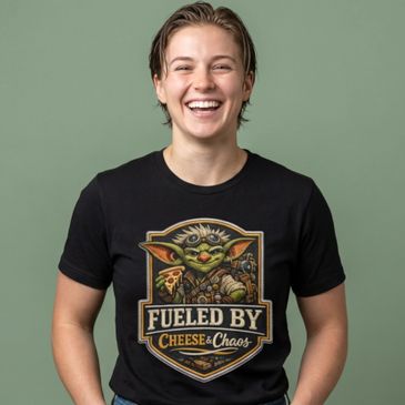 Person smiling wearing a black "Fueled by Cheese &amp; Chaos" t-shirt with a baby Yoda graphic.