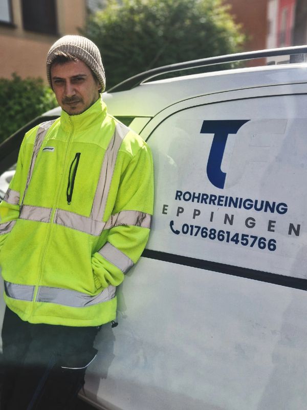 Man in yellow safety jacket leaning against a work van with Rohrreinigung Eppingen logo.