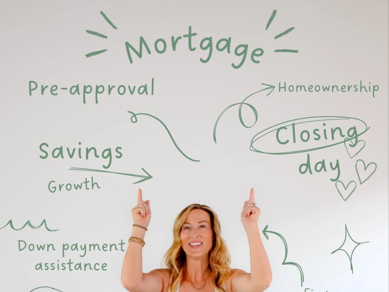 Woman sitting on a chair pointing at mortgage-related words on the wall.