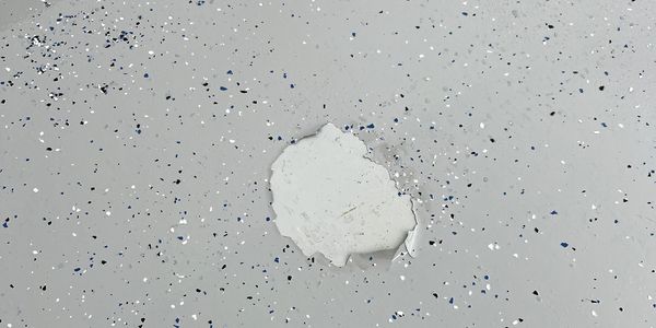 Failed DIY epoxy floor which lead to a ripped/bear spot revealing the old floor underneath.