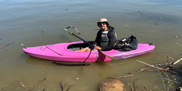 Person kayaking in a pink kayak on calm water.