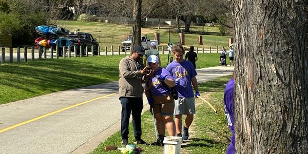Group outdoors on a sunny day, wearing purple shirts.