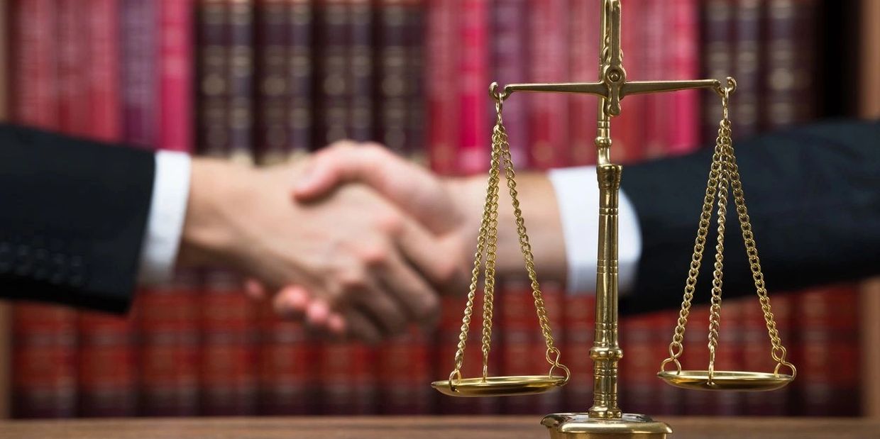 Justice scale on table with judge and client shaking hands 