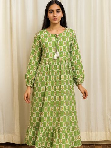 Woman in a green and white checkered floral dress with tassel details.