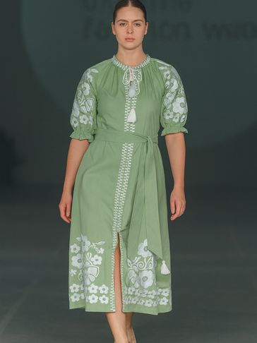 Model in a green midi dress with white floral embroidery and puff sleeves.