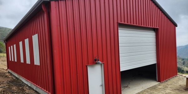 Quintessential red barn with 3:12 roof slope, overhead garage door, walk door & luminous wall lites 