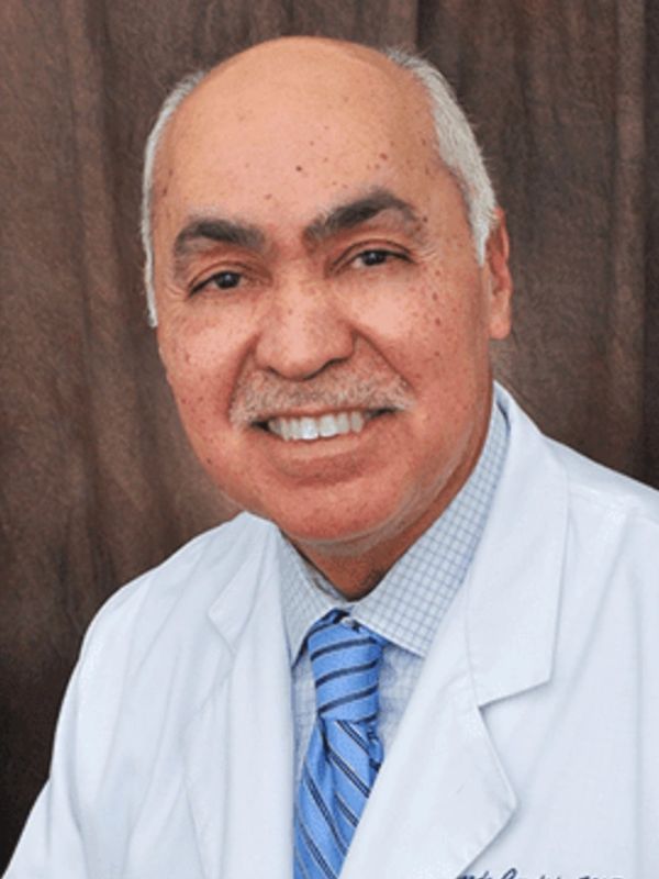 Smiling male doctor in white coat with blue tie.
