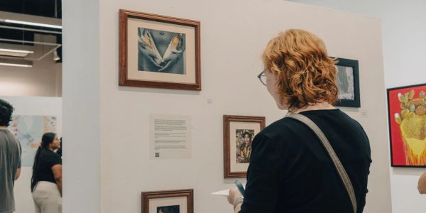 Visitor viewing framed artwork during a Casa Azul gallery exhibition.