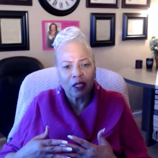 Woman speaking passionately during a video call in a cozy home office.