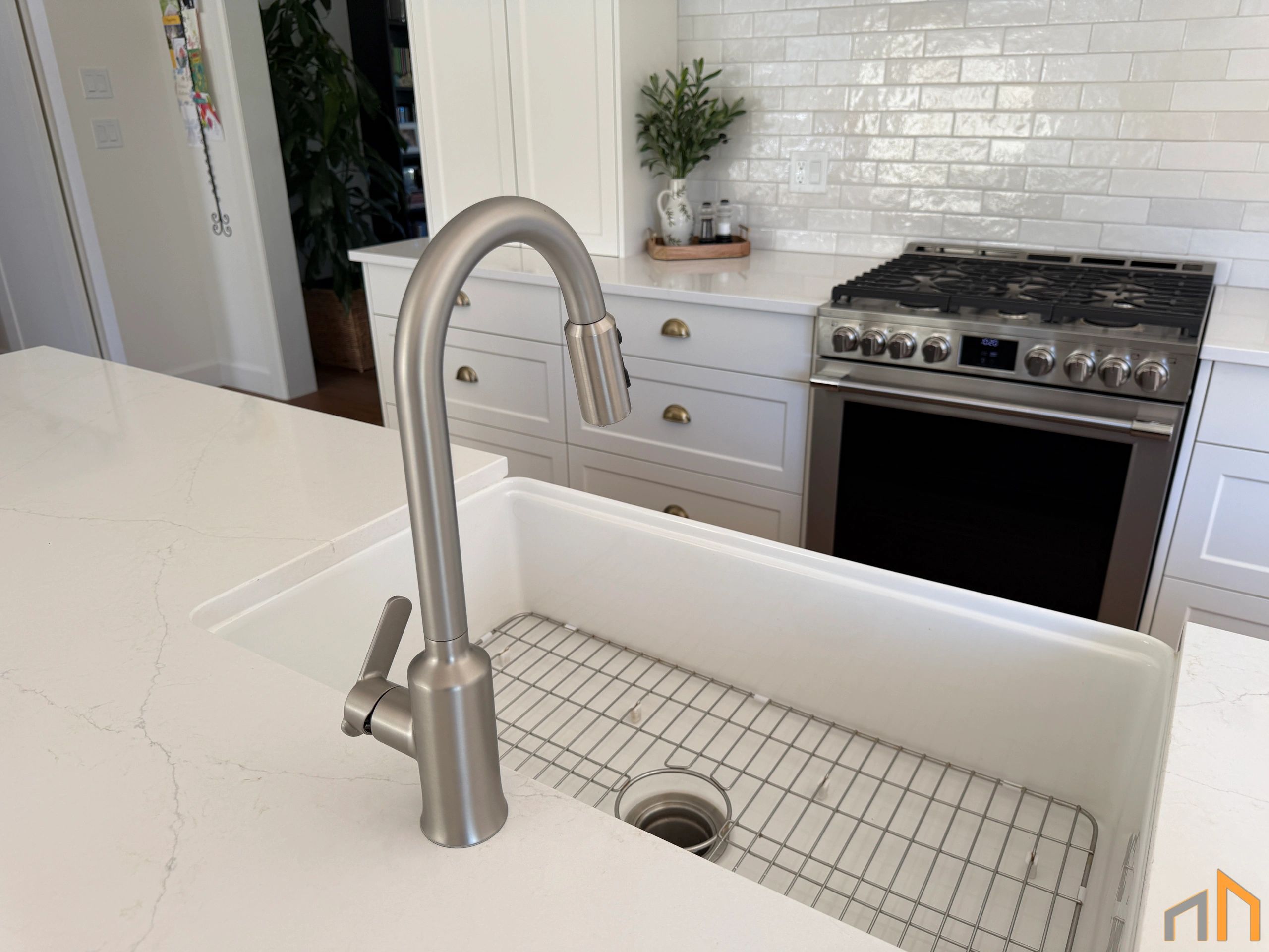 Modern kitchen sink with a stainless steel faucet and white countertop.