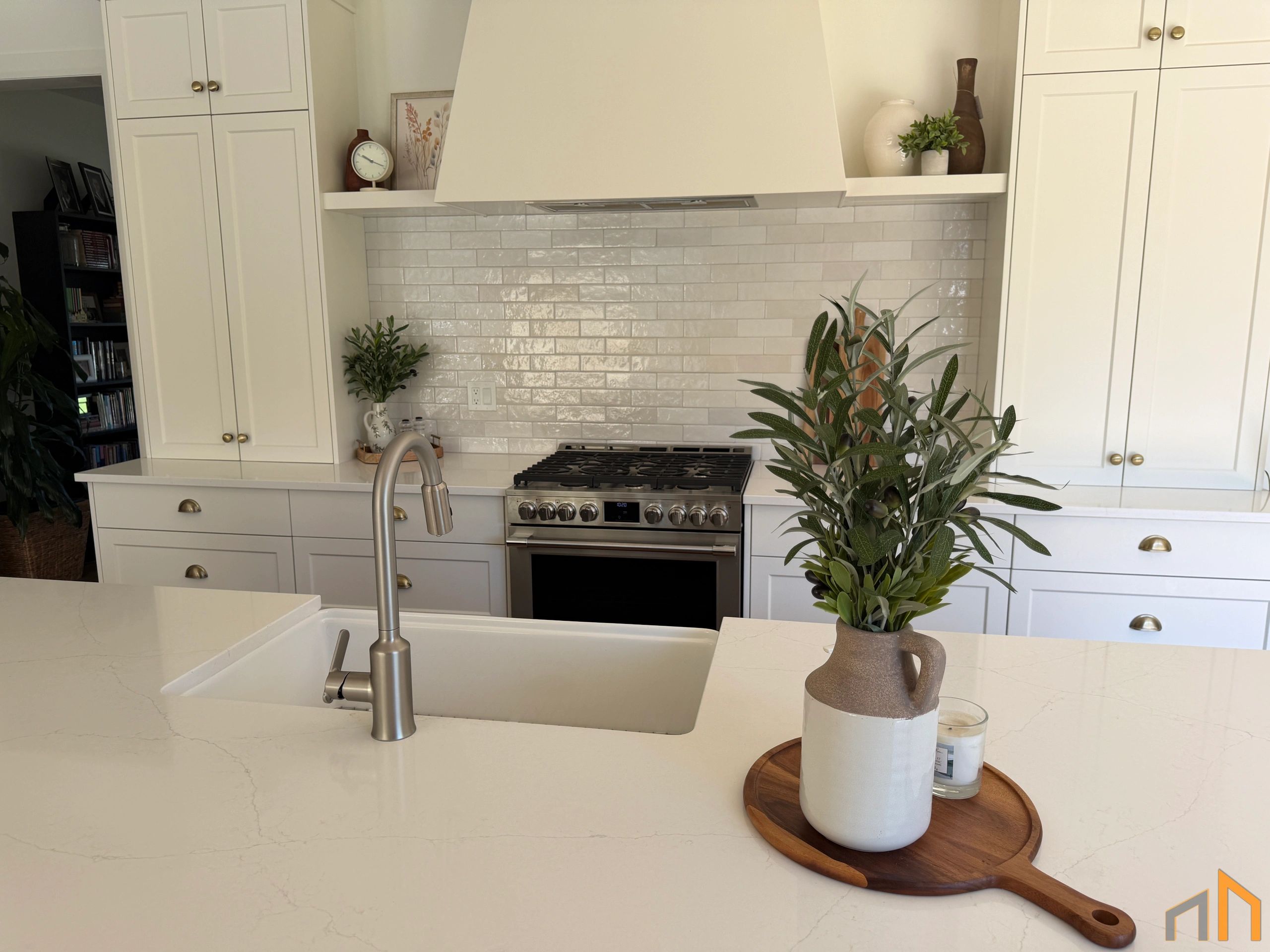 Modern white kitchen with a central island and decorative plants.